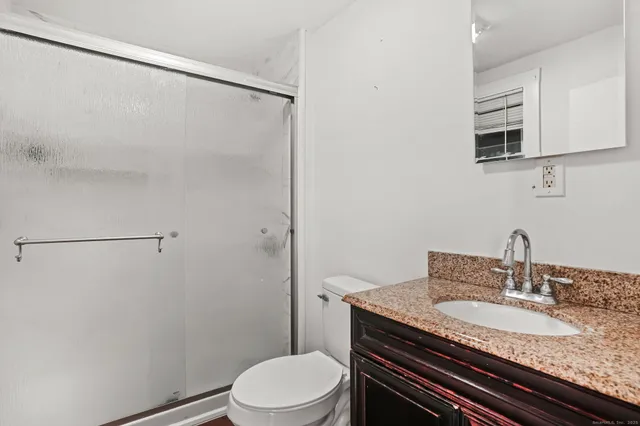 a bathroom with a granite countertop sink toilet and shower