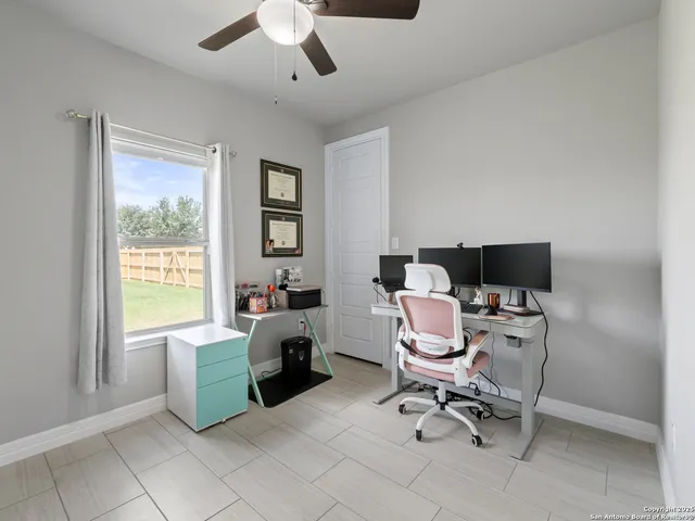 a view of a workspace with furniture and a ceiling fan