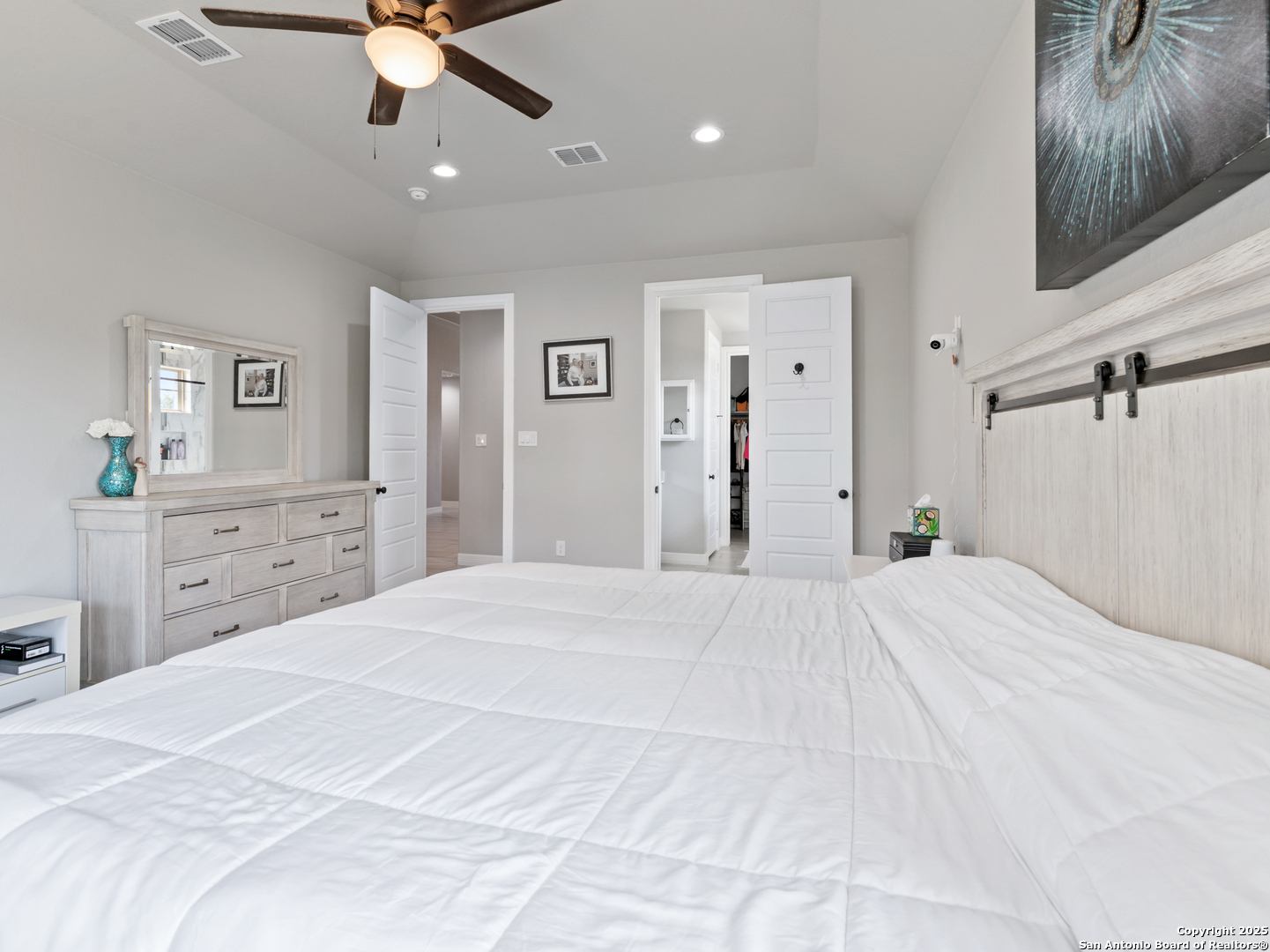 132 West Medium Meadow Drive Lytle, TX 78052 - Photo 31 of 46 a bedroom with a large bed and a chandelier