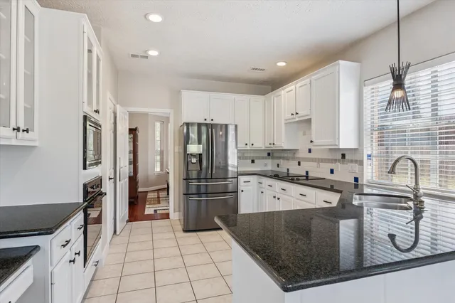a spacious bathroom with a granite countertop double vanity sink a mirror and a bathtub