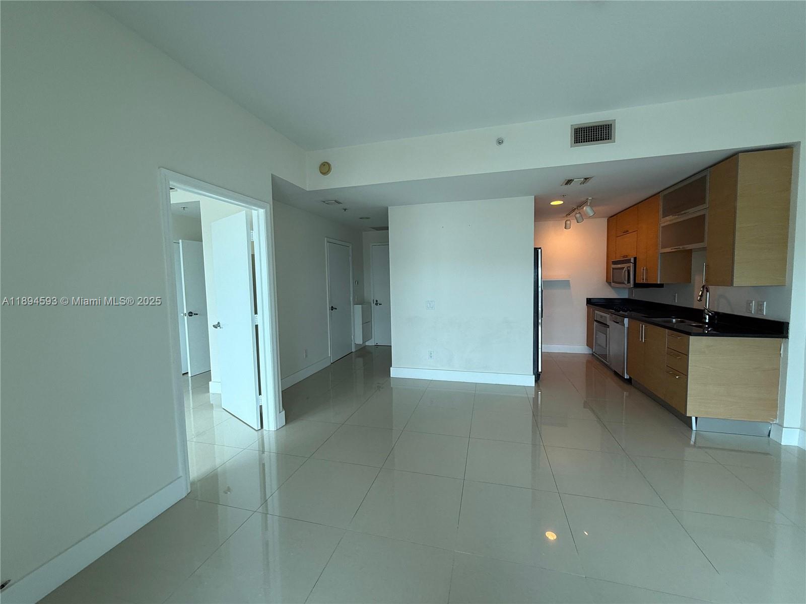 60 Southwest 13th Street, Unit 3809 Miami, FL 33130 - Photo 2 of 6 a view of kitchen with refrigerator and white cabinets