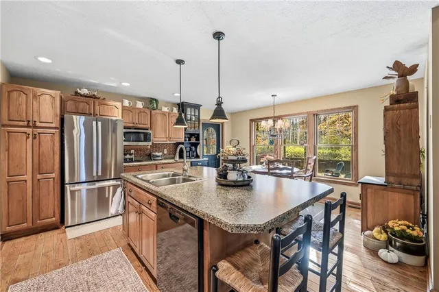 a kitchen with stainless steel appliances granite countertop a kitchen island a stove and a sink