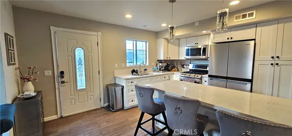 a kitchen with stainless steel appliances granite countertop a refrigerator a sink a stove a dining table and chairs