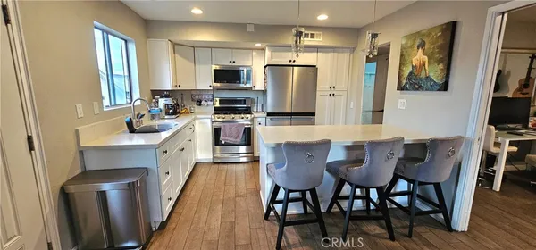 a kitchen with stainless steel appliances a dining table chairs microwave and sink