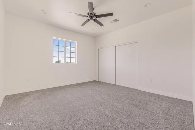 an empty room with a window and a ceiling fan