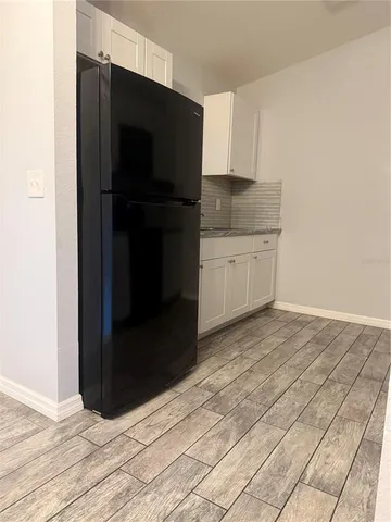 a kitchen with granite countertop white cabinets and refrigerator