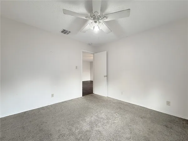 an empty room with a chandelier fan and windows
