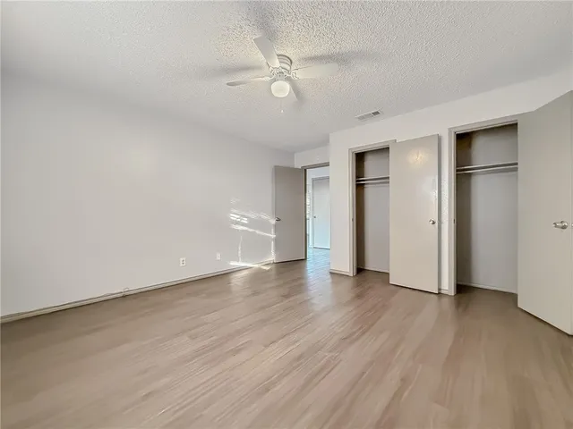 an empty room with wooden floor and a ceiling fan