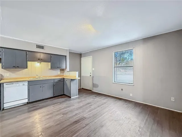 a large kitchen with a wooden floor and stainless steel appliances