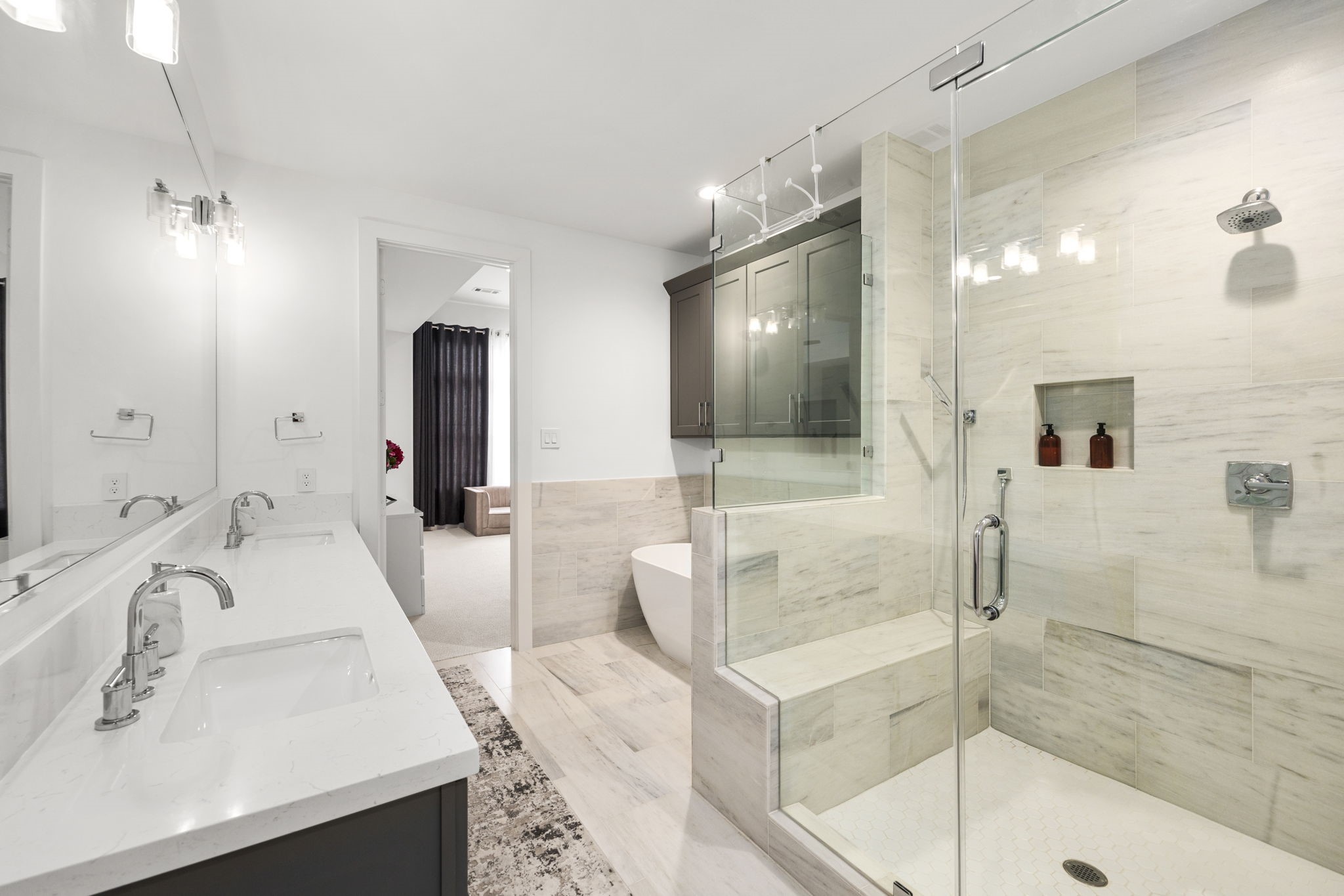 2411 Hazard Street Houston, TX 77019 - Photo 30 of 46 This primary ensuite bathroom offers a luxurious retreat, featuring dual sinks, a spacious glass-enclosed shower with built-in seating, and a deep soaking tub. The modern fixtures and clean lines create an elegant, spa-like atmosphere, perfectly complementing the serene aesthetic of the primary bedroom.