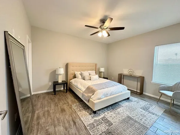 a bedroom with a bed a rug a table and a large mirror