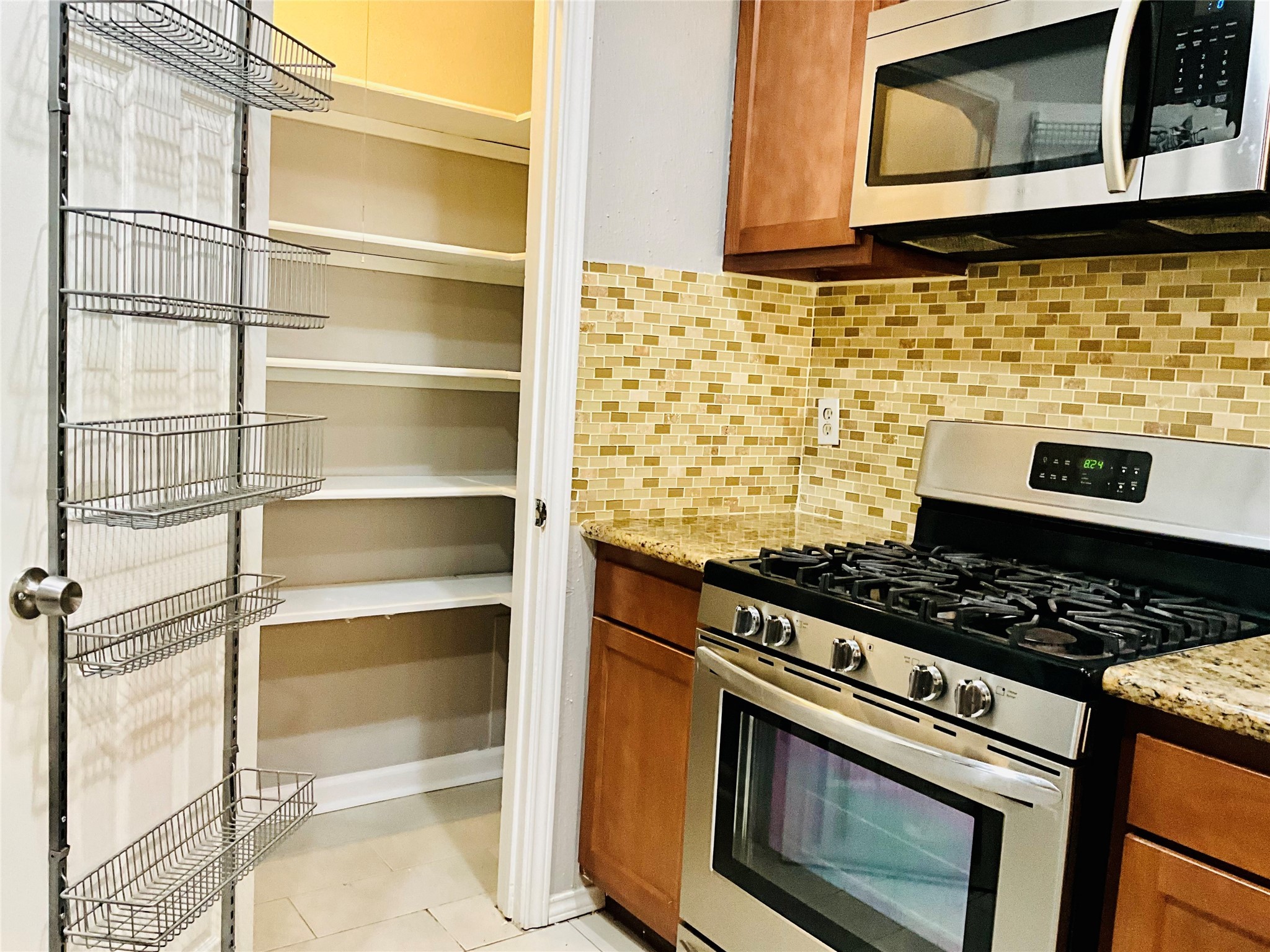 11827 Moss Branch Road Houston, TX 77043 - Photo 12 of 41 a kitchen with granite countertop cabinets stove and microwave