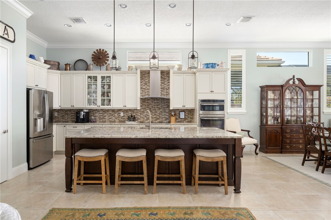 1101 River Wind Circle Vero Beach, FL 32967 - Photo 13 of 36 a kitchen with stainless steel appliances kitchen island granite countertop a table and chairs in it