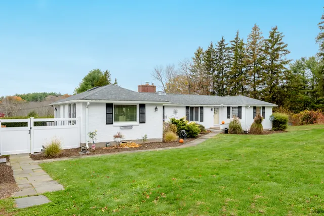 a front view of a house with a garden and trees
