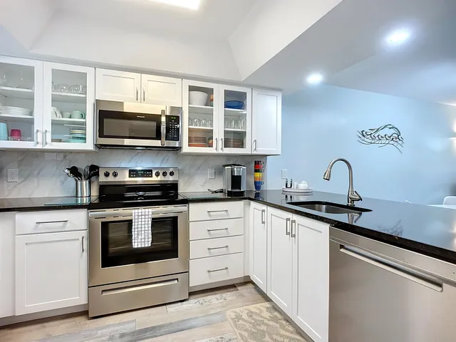 a kitchen with stainless steel appliances granite countertop a stove top oven a sink dishwasher a refrigerator and a microwave oven