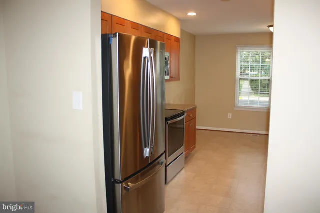 a view of empty room with windows and refrigerator
