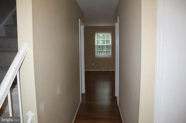 a view of a hallway with wooden floor and a bathroom