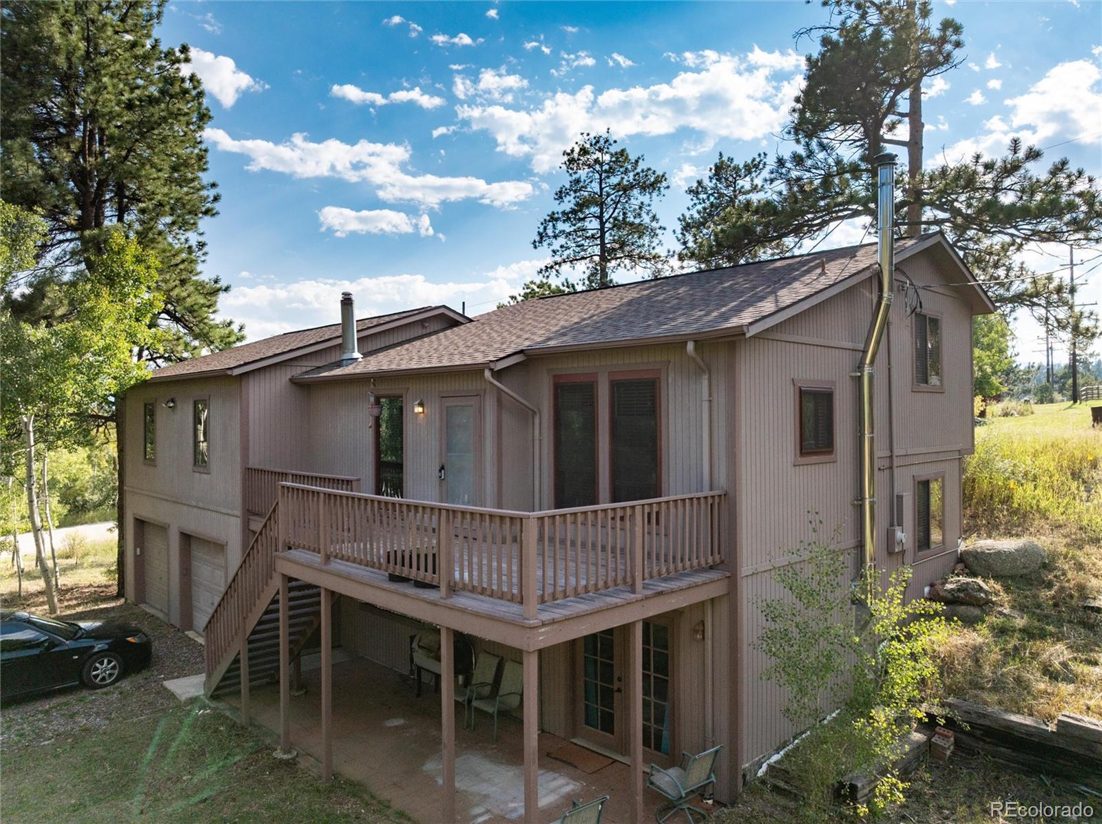 a view of a house with a wooden deck and a tree