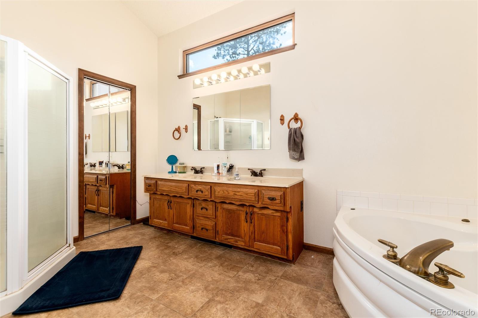 65 Silver Springs Road Bailey, CO 80421 - Photo 7 of 38 a spacious bathroom with a double vanity sink a mirror and a bathtub