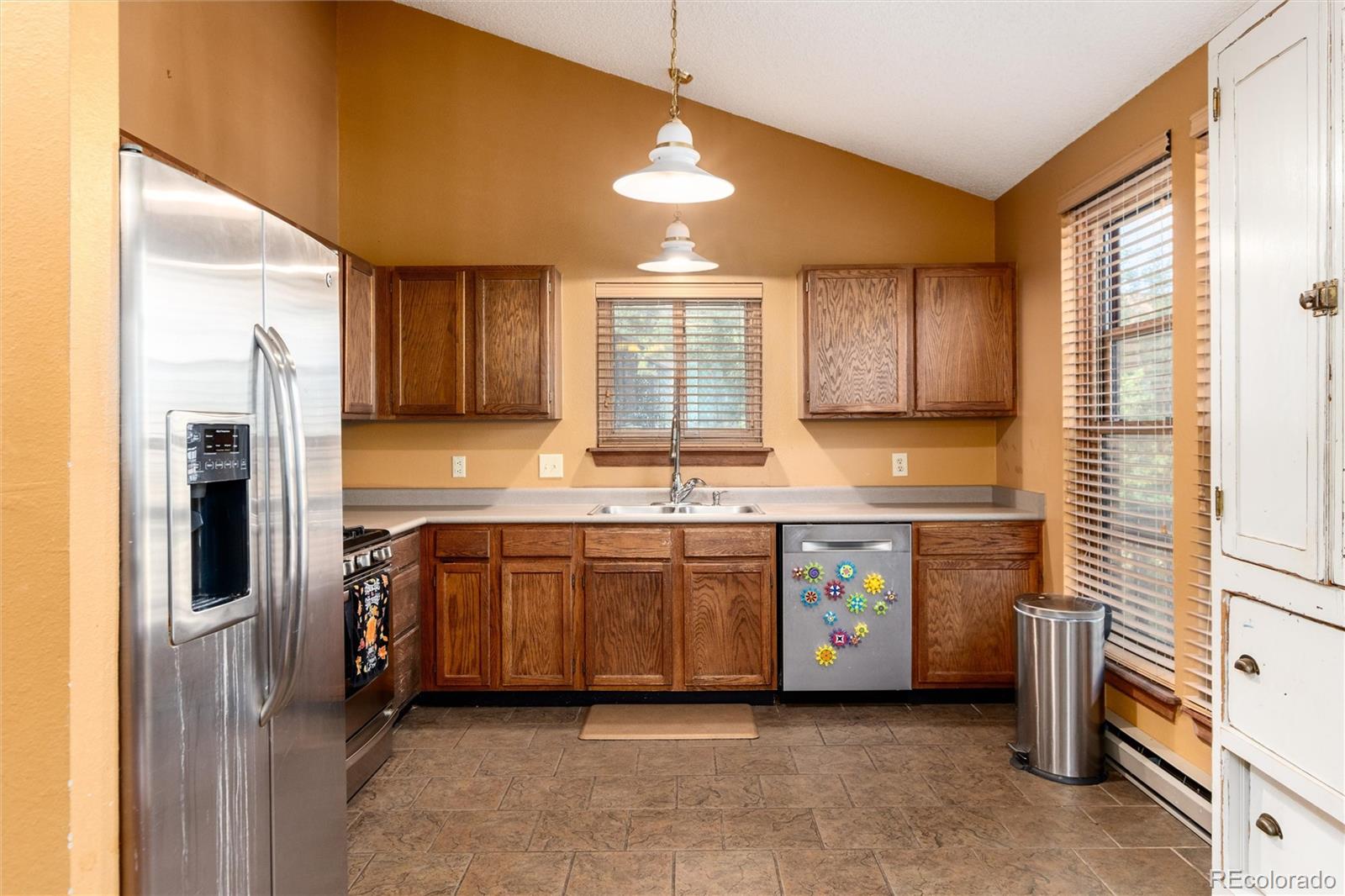 65 Silver Springs Road Bailey, CO 80421 - Photo 9 of 45 a kitchen with stainless steel appliances granite countertop a refrigerator a sink dishwasher a stove and white countertops with wooden floor