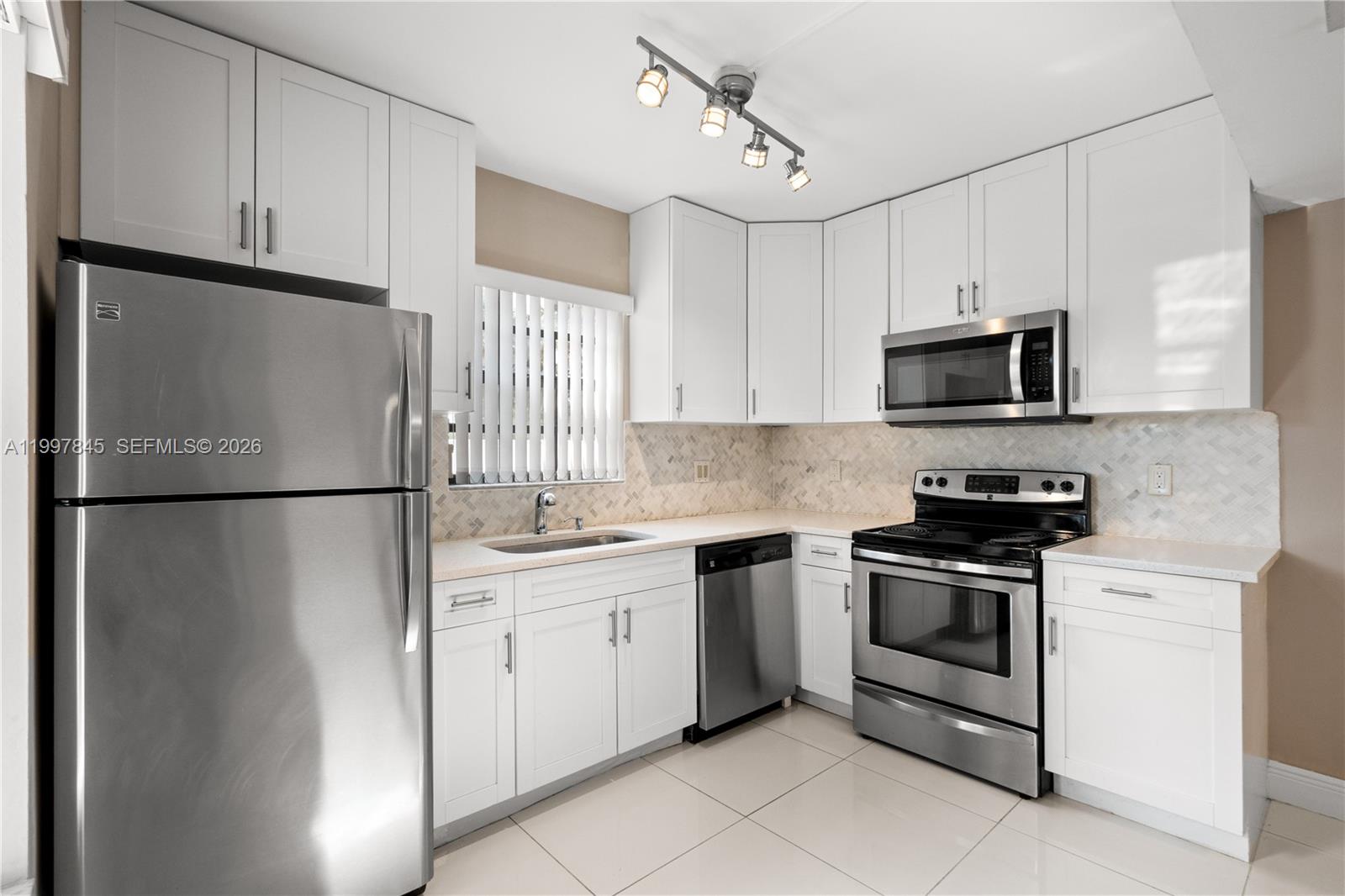 6211 Southwest 138th Court, Unit B Miami, FL 33183 - Photo 9 of 27 a kitchen with stainless steel appliances granite countertop white refrigerator stove a sink and a microwave