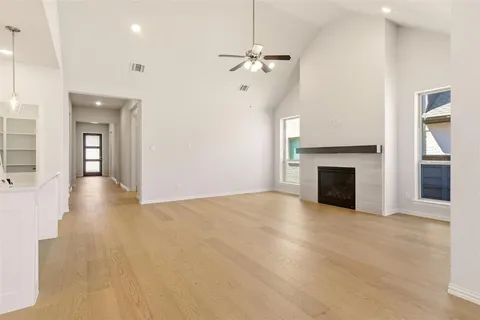 a view of an empty room with wooden floor fireplace and a window