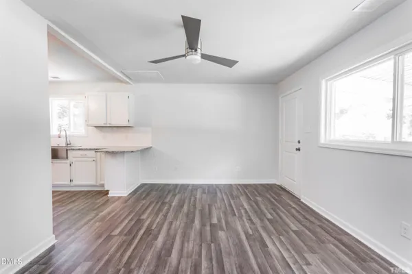 a view of kitchen and empty room with wooden floor