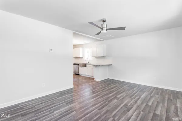 a view of kitchen and empty room with wooden floor
