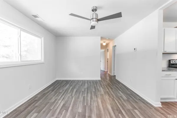 a view of a room with wooden floor a ceiling fan and windows