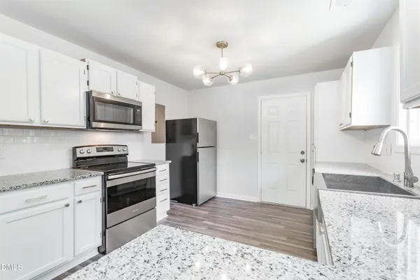 a kitchen with stainless steel appliances granite countertop a stove a refrigerator and a sink