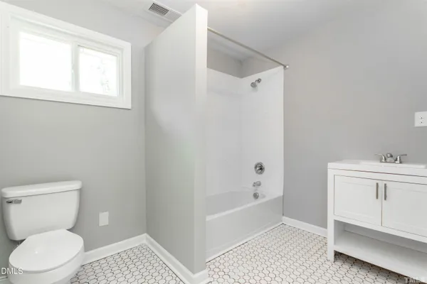 a bathroom with a toilet a sink a window and vanity
