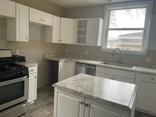 a kitchen with stainless steel appliances granite countertop a sink stove and microwave