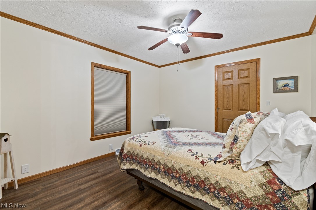 2240 Prysi Road Northwest Dover, OH 44622 - Photo 25 of 35 Bedroom featuring ceiling fan, ornamental molding, dark hardwood / wood-style floors, and a textured ceiling