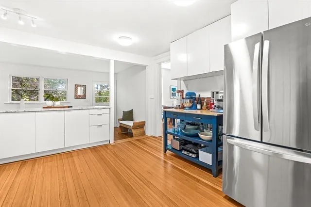 a kitchen view with stainless steel appliances a refrigerator and a wooden floor