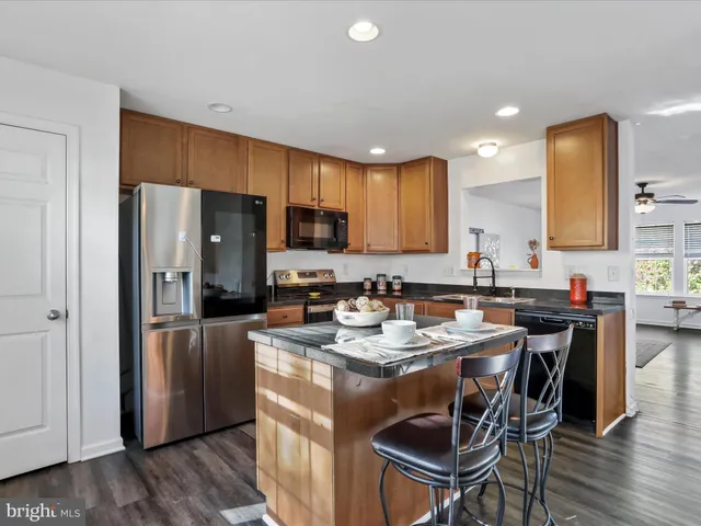 a kitchen with a refrigerator a stove a sink a dining table and chairs