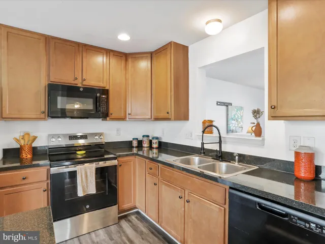 a kitchen with stainless steel appliances granite countertop a sink a stove a microwave oven with cabinets and wooden floor