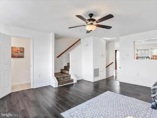 a view of an empty room with wooden floor and stairs