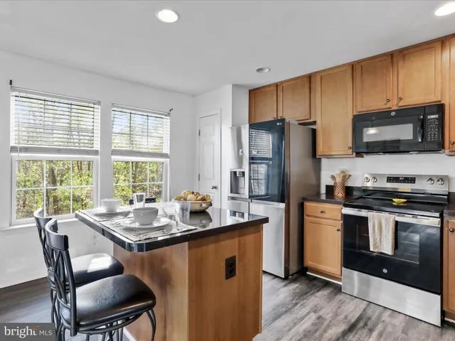 a kitchen with stainless steel appliances granite countertop a stove a refrigerator a sink a dining table and chairs