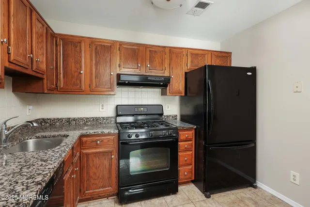 a kitchen with granite countertop a stove top oven cabinetry a sink and dishwasher