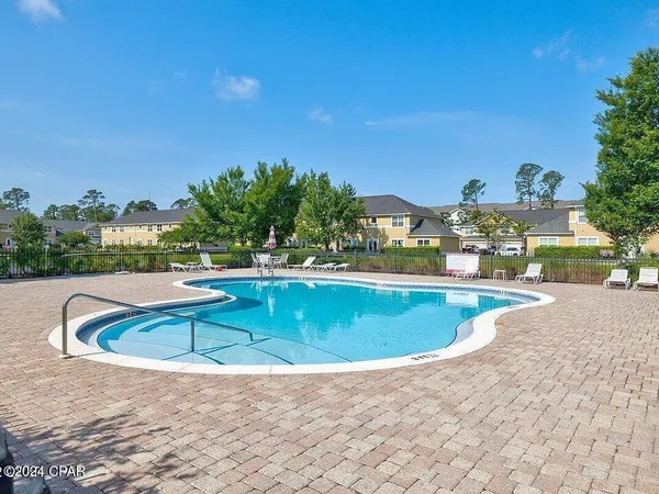 a view of swimming pool with outdoor seating and trees in the background