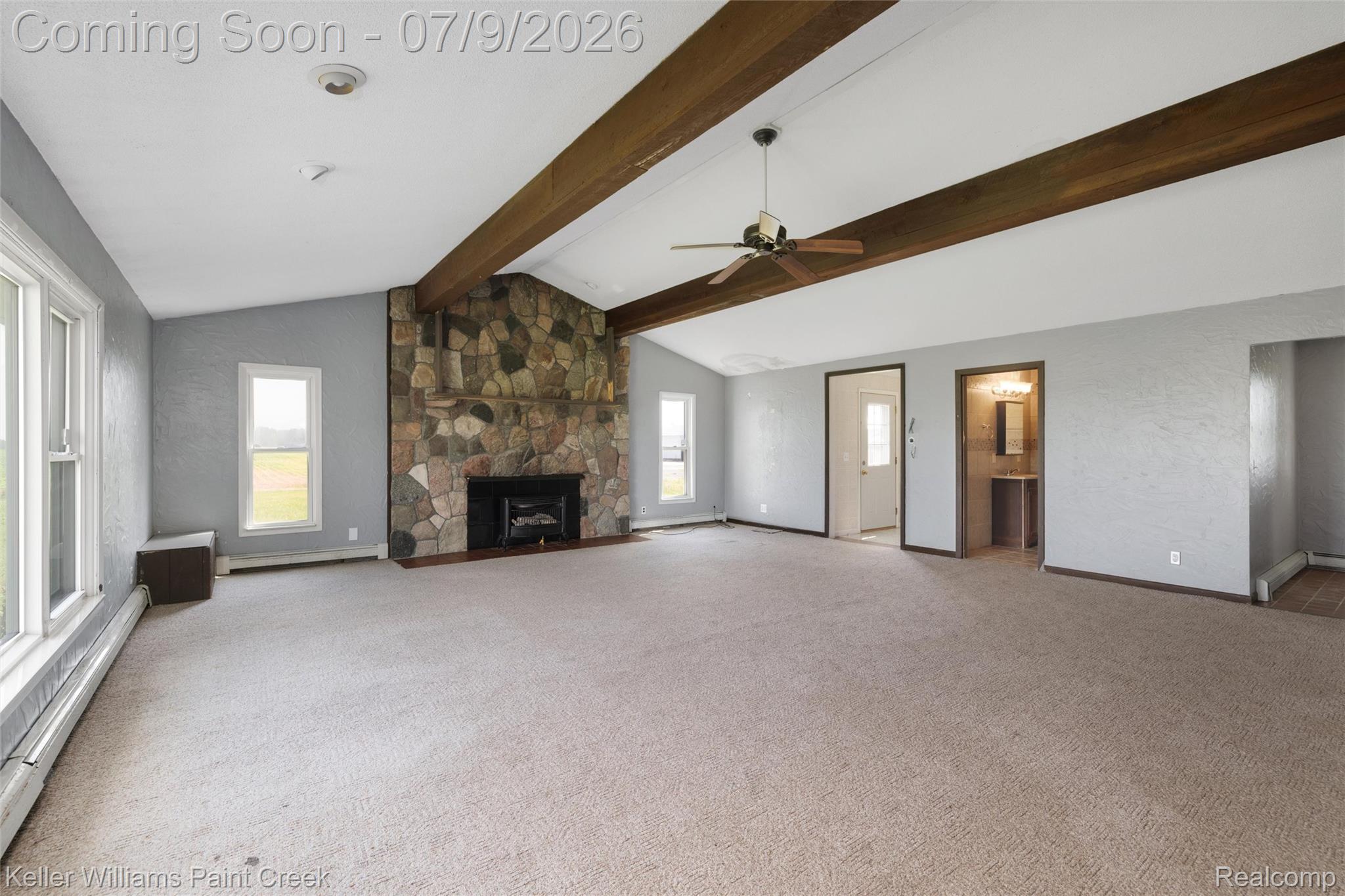 28780 School Section Road Richmond, MI 48062 - Photo 21 of 50 Spacious living area featuring a stone-clad fireplace, exposed wood ceiling beams, vaulted ceilings, and light tan carpeting