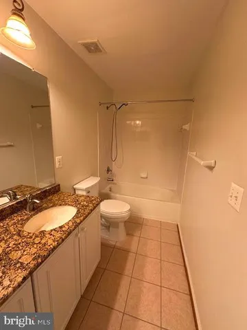 a bathroom with a granite countertop sink a toilet and a shower