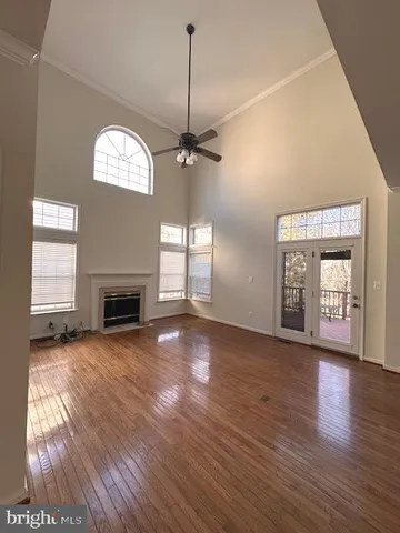a view of an empty room with wooden floor fireplace and a window