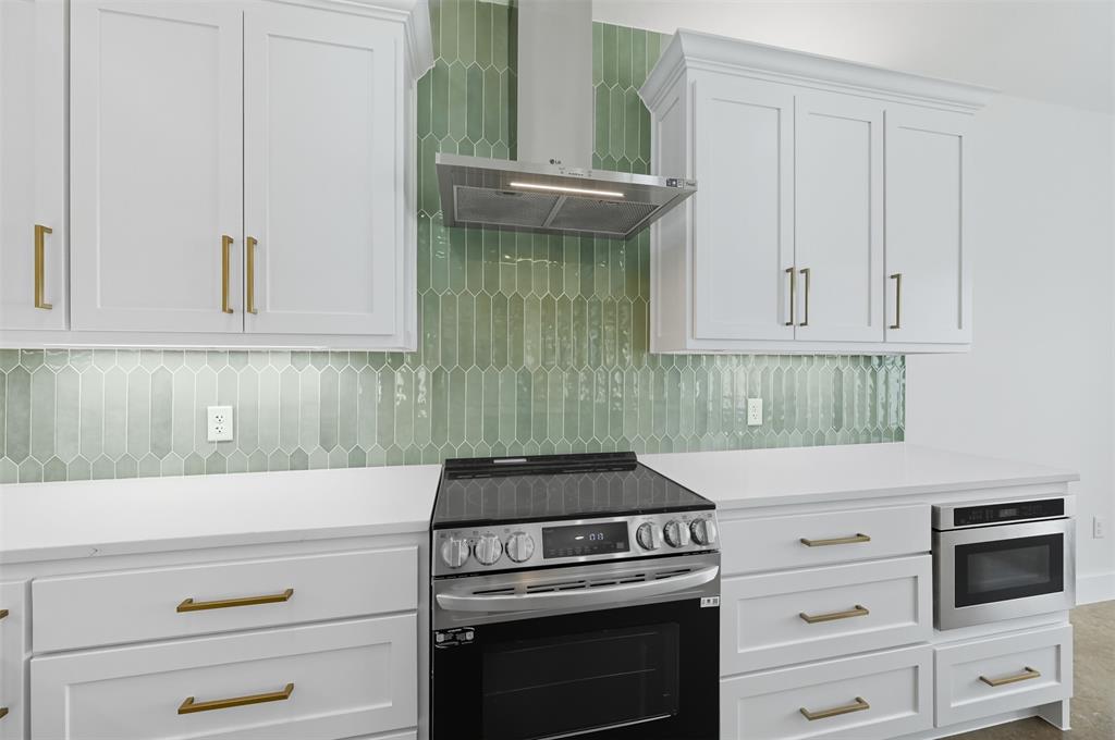 100 Cardinal Wds Granbury, TX 76049 - Photo 6 of 36 Kitchen featuring appliances with stainless steel finishes, white cabinets, wall chimney range hood, and decorative backsplash