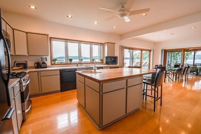 a kitchen with a stove a sink a counter top space and living room view