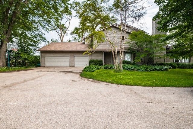 a front view of a house with a garden and trees