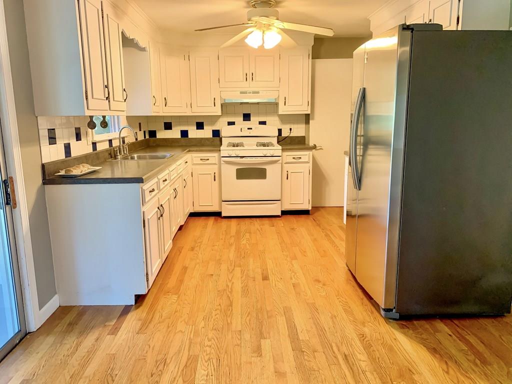 896 Tinkham Road Wilbraham, MA 01095 - Photo 5 of 30 a kitchen with stainless steel appliances a refrigerator a sink dishwasher and white cabinets with wooden floor