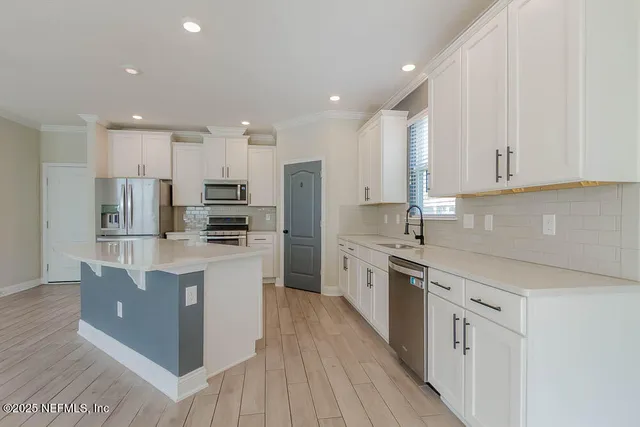 a kitchen with stainless steel appliances granite countertop a refrigerator oven a sink dishwasher and white cabinets with wooden floor