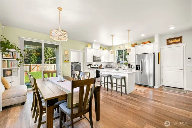 a view of a dining room and livingroom with furniture a chandelier and wooden floor