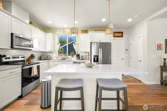 a kitchen with stainless steel appliances granite countertop a table chairs sink and cabinets